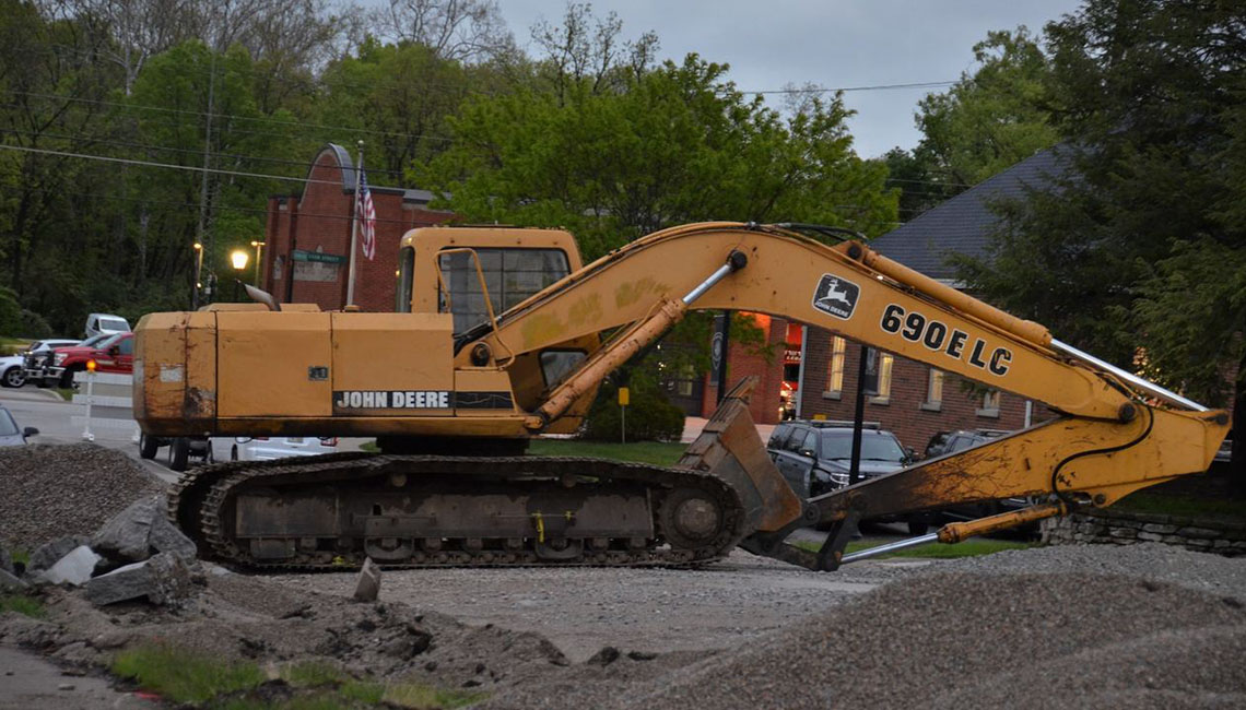 A yellow John Deere 690E LC excavator at a construction site with debris.