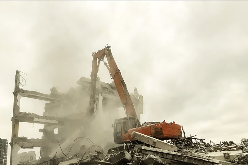 Excavator tearing down an old building during a professional demolition project.